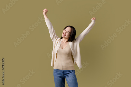 Happy asian woman doing win gesture isolated on green 
