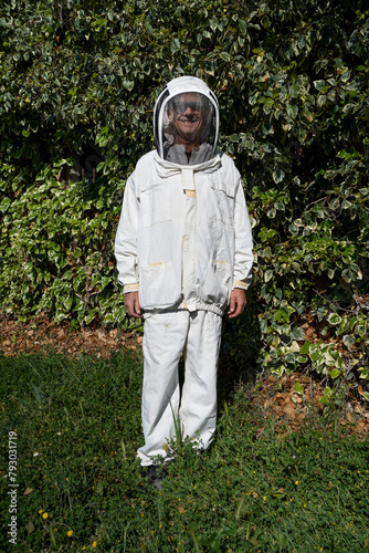 Portrait of beekeeper looking at camera smiling and posing, futuristic protective suit with astronaut-like helmet.