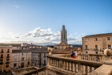 Pareja de turistas contemplando la belleza del barrio viejo de Gerona con las vistas desde la Catedral a la Basílica de Sant Félix, Cataluña