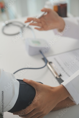 Male doctor uses a blood pressure monitor to check the body pressure and pulse of the patients who come to the hospital for check-ups, Medical treatment and health care concept.