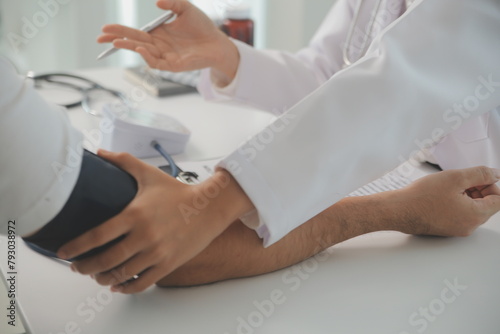 Male doctor uses a blood pressure monitor to check the body pressure and pulse of the patients who come to the hospital for check-ups  Medical treatment and health care concept.