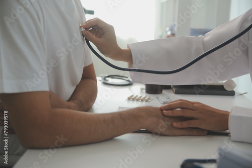 Young doctor is using a stethoscope listen to the heartbeat of the patient. Shot of a female doctor giving a male patient a check up photo