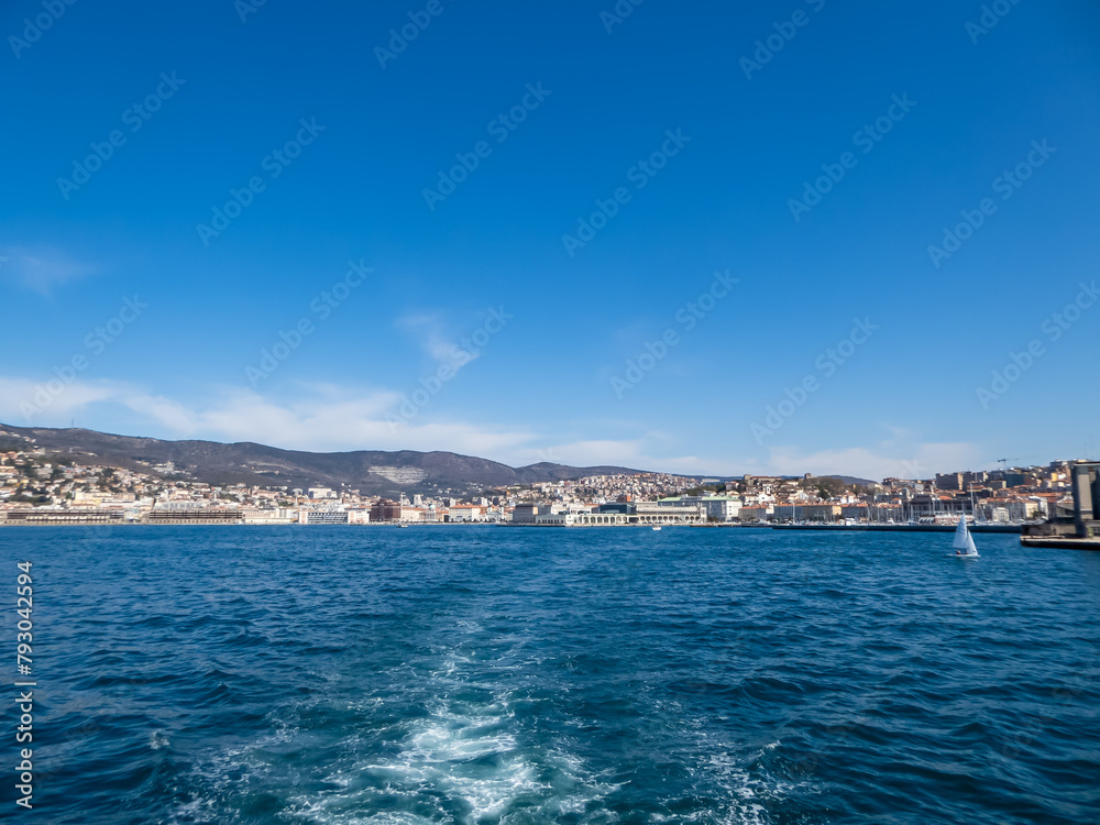 Scenic view from a ferry of the port of Trieste from in Friuli-Venezia Giulia, Italy, Europe. Blue sky in tranquil atmosphere at Adriatic Mediterranean sea in summer. Boat tour along the coastline