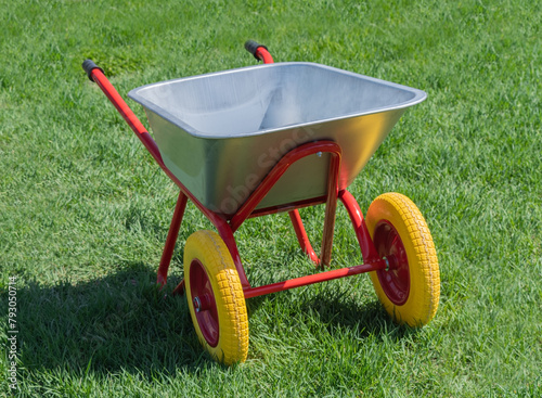 Garden metal wheelbarrow on a lawn with grass
