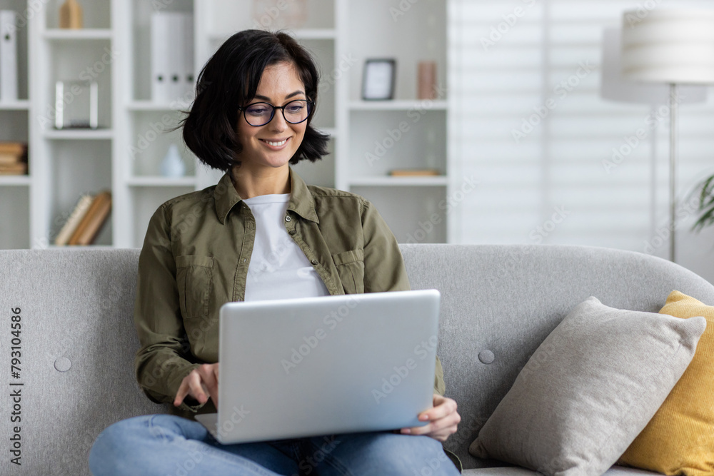 Happy woman working on laptop in a cozy living room Happy woman working on laptop in a cozy living room