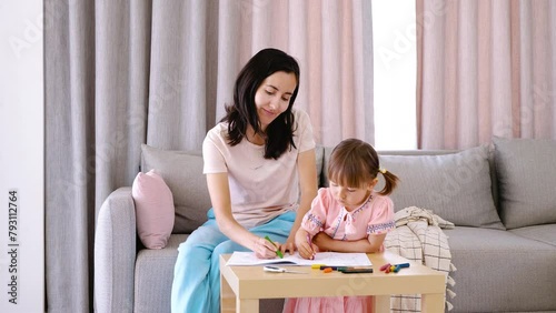 Nanny babysitter draws with pencils together with the child. Education and development of toddler children