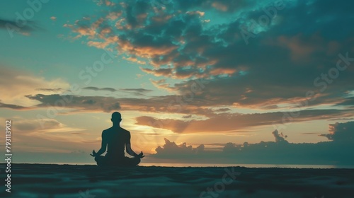 A serene scene of an individual practicing meditation at sunrise, their silhouette against the calming hues of the morning sky, embodying tranquility and mindfulness. © Sasint