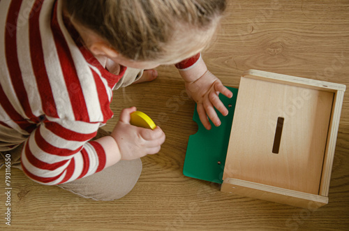 Enfant qui joue avec une boite permanence de l'objet Montessori