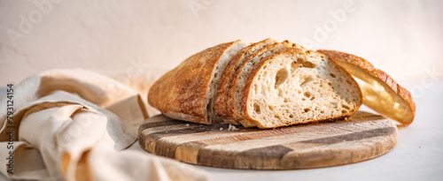 Canvas-taulu A loaf of freshly sliced sourdough bread on a wooden board, with a cloth beside it