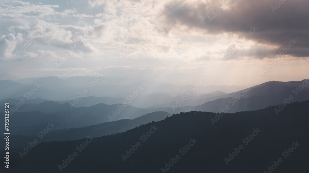 The sky is cloudy and the mountains are in the background. The mountains are covered in trees and the sky is a mix of blue and gray