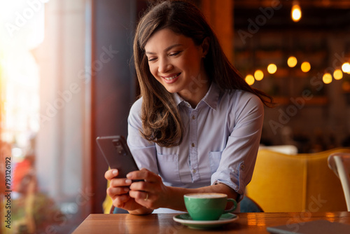 Business woman using phone in coffee shop