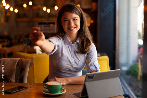 Portrait of woman holding credit card in coffee shop