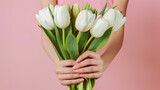 Woman hands holding bunch of beautiful white spring tulips on pale pink background