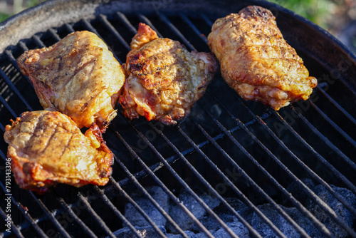Chicken thighs cooking on a charcoal grill. Selective focus, background blur, foreground blur