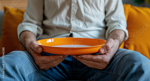 A starving old man with orange plate and waiting for his meal at home photo