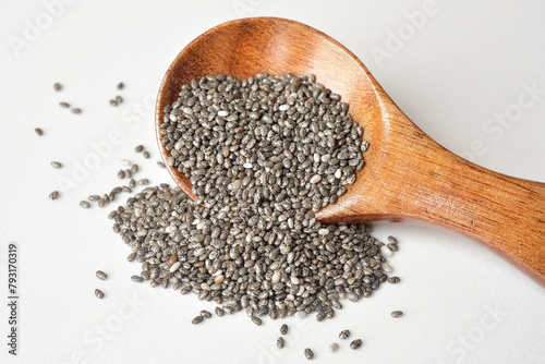 Close up of chia seeds in a wooden spoon on white background. Chia seeds contain fibre and omega-3 fatty acids, protein, many essential minerals and antioxidants. Healthy eating concept. photo