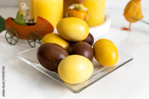 Easter eggs, yellow candles and souvenirs on a white table. Photo
