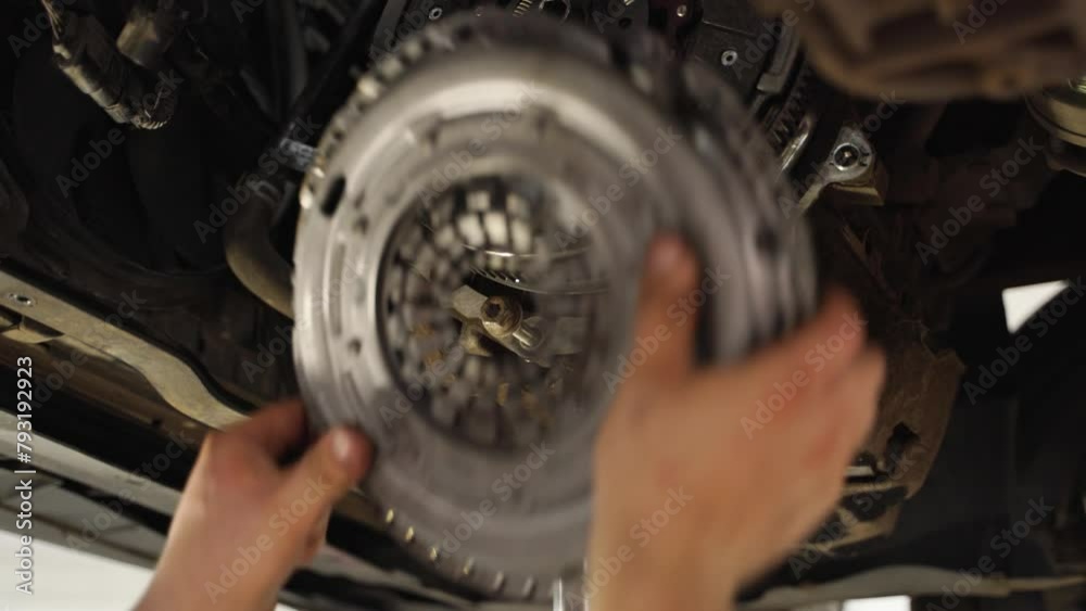 Mechanic installs new clutch disc in car. Automotive repair workshop scene, hands replace worn components. Vehicle maintenance, clutch assembly, gearbox service. DIY auto workshop instruction.