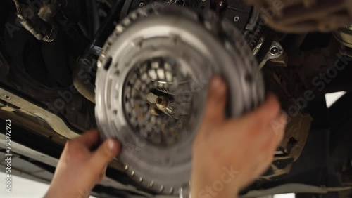 Mechanic installs new clutch disc in car. Automotive repair workshop scene, hands replace worn components. Vehicle maintenance, clutch assembly, gearbox service. DIY auto workshop instruction.