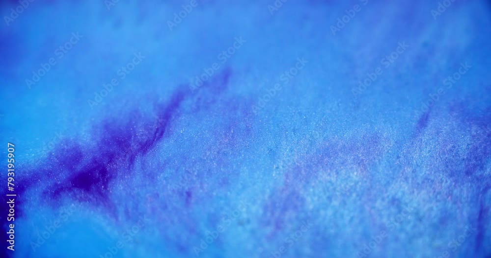 Glitter fluid flow. Sparkling paint. Defocused blue purple color holographic gloss shiny dust sand particles blend water ink wave motion abstract art background.