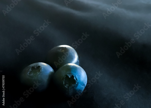 Three blueberries on a black background with bokeh