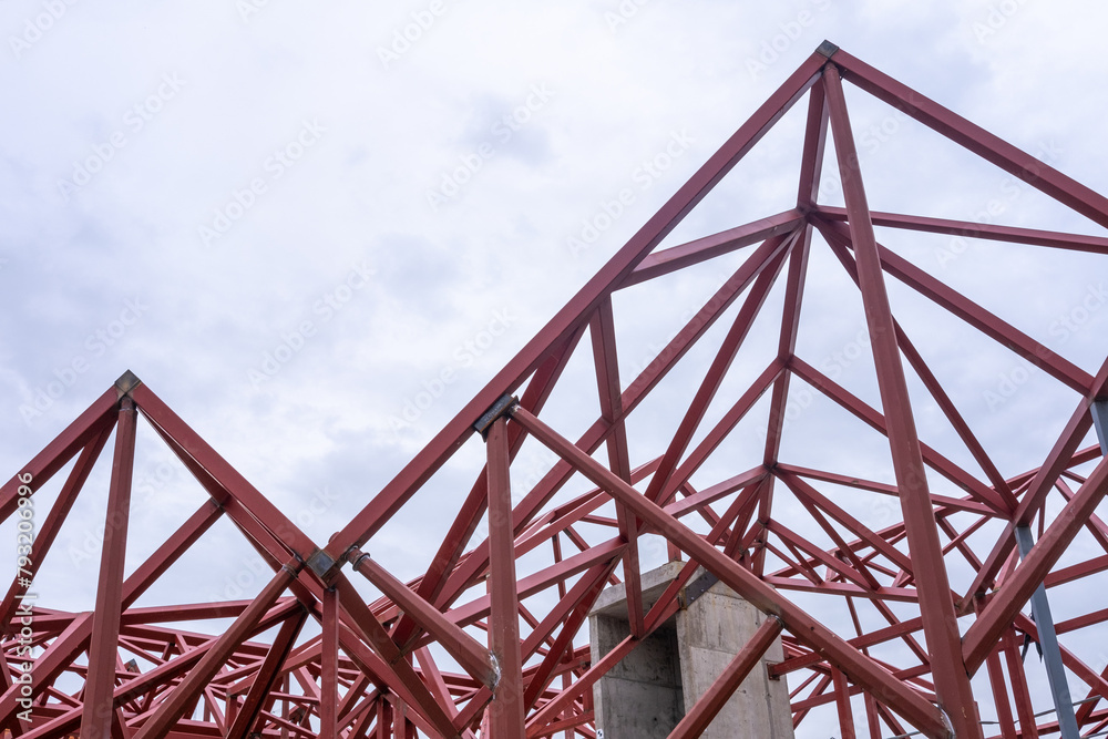 Geometric composition of red metal beams in a modern construction against a clear sky with copy space