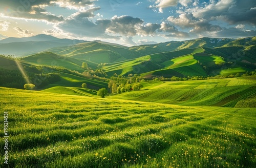  A lush green hillside, blanketed in grass, unfolds beneath a cloud-studded, blue-tinted sky Sunrays pierce the clouds