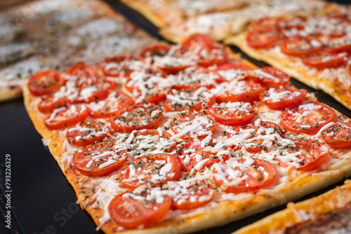 Close up. Portion pizza with tomatoes and cheese on showcase. Barcelona street food.