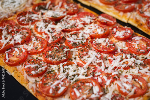 Close up, macro. Portion square pizza with tomatoes and cheese. Spanish street food.