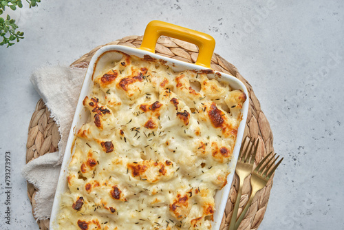 A cheesy macaroni and cheese cauliflower casserole in a yellow handled dish