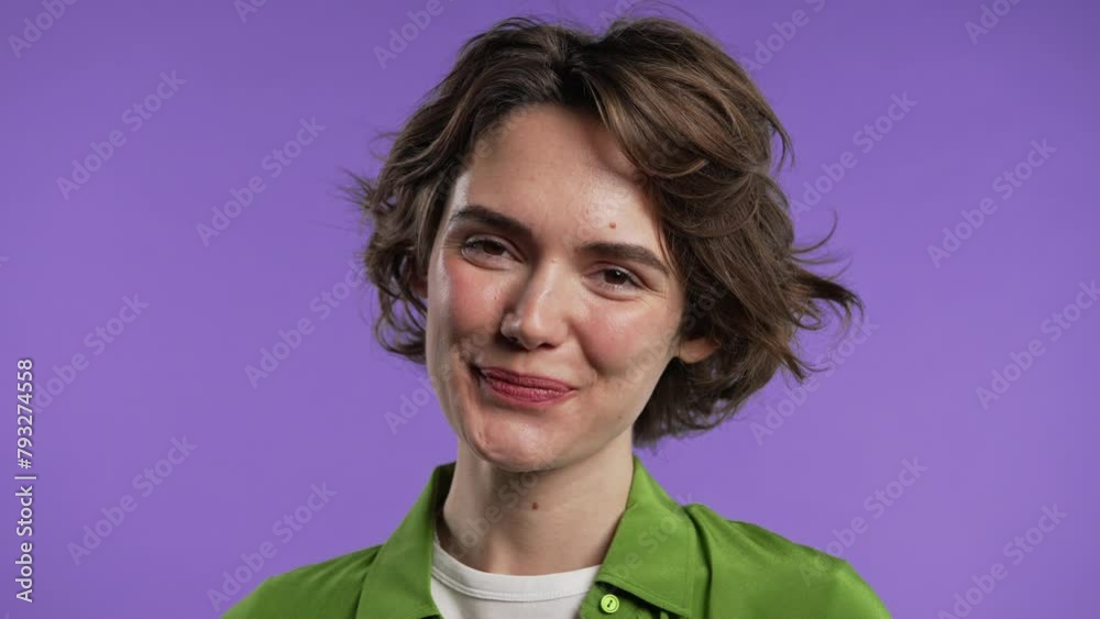 Young charming woman looking to camera and smiling on violet background. Face. Young charming woman looking to camera and smiling on violet background. Face.
