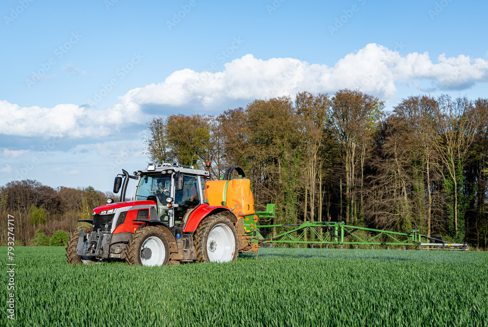 Pflanzenschutz im Ackerbau - roter Traktor mit Feldspritze im Getreidefeld, Frontansicht. Pflanzenschutz im Ackerbau - roter Traktor mit Feldspritze im Getreidefeld, Frontansicht.