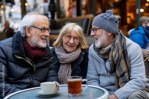 Group of senior friends sitting at a table in a street cafe, drinking coffee and talking