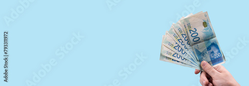 Hand holding stack of cash bills, New Israeli Shekels (NIS), representing financial wealth, abundance, and prosperity in Israel. photo
