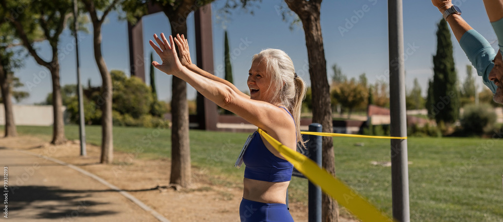 Obraz premium Senior woman crosses finish line winning outdoor marathon championship while celebrating by raising her arms