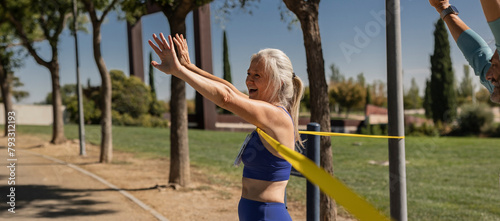 Senior woman crosses finish line winning outdoor marathon championship while celebrating by raising her arms