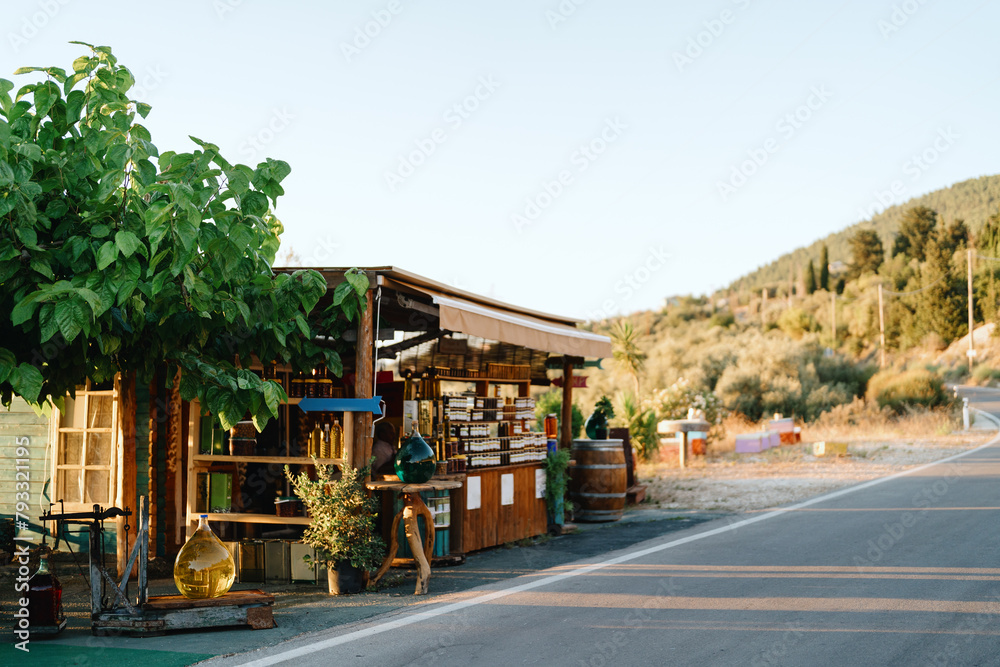 A charming little roadside stand offers local goods under the bright summer sun, nestled in lush greenery.