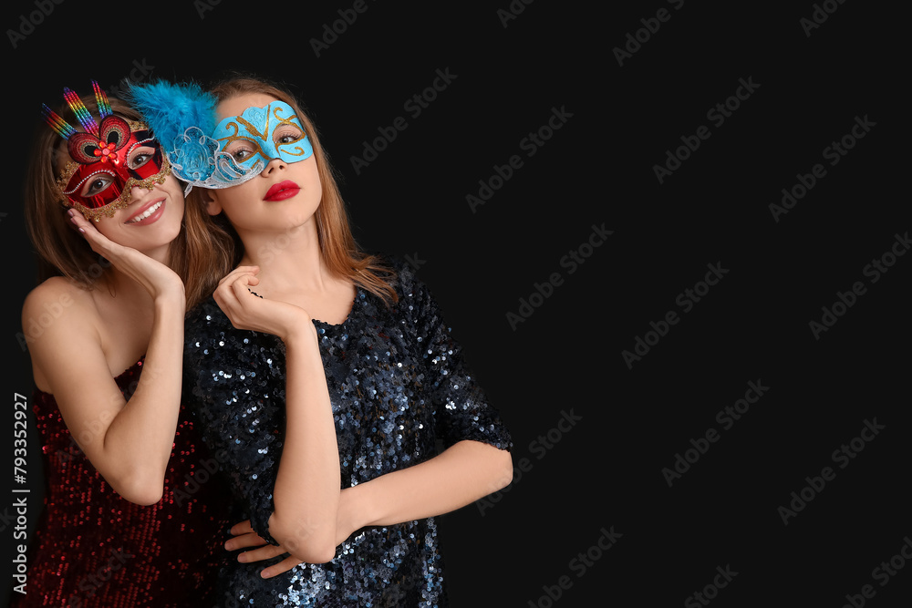 Obraz premium Beautiful young women in carnival masks on black background