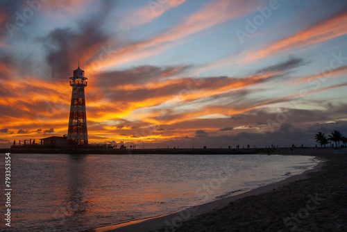 Sunset on the shore of a Bahamian beach with the sun falling on the horizon. Lighthouse backlit.Summer holiday concept