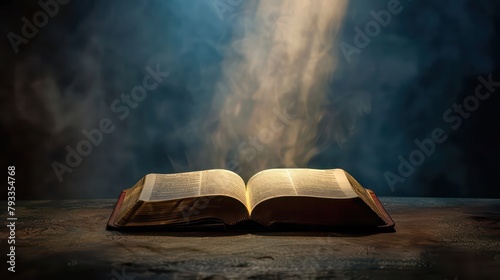 Open bible on a dark background with rays of light and smoke photo