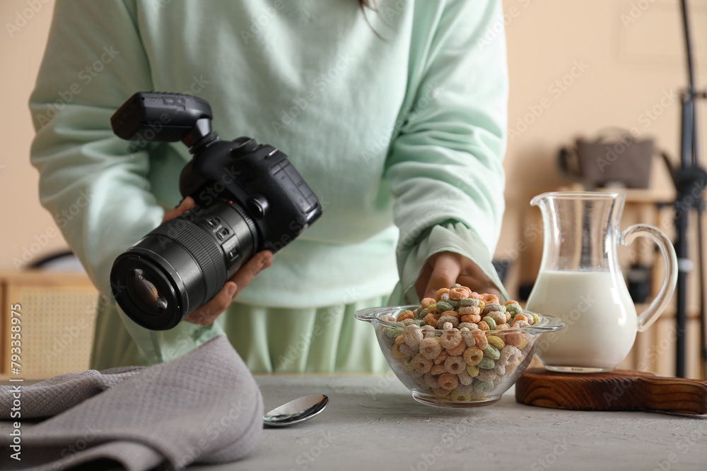 Fototapeta premium Female food photographer preparing for shooting tasty cereal rings with milk in studio, closeup