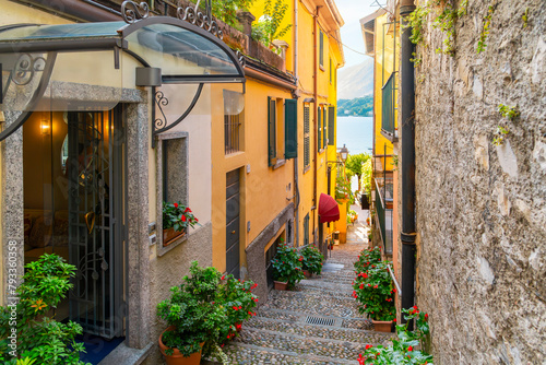 A narrow cobblestone alley with steps leading to the lake on a steep staircase with shops and cafes in the historic old town of Bellagio, Italy, on the shores of Lake Como.