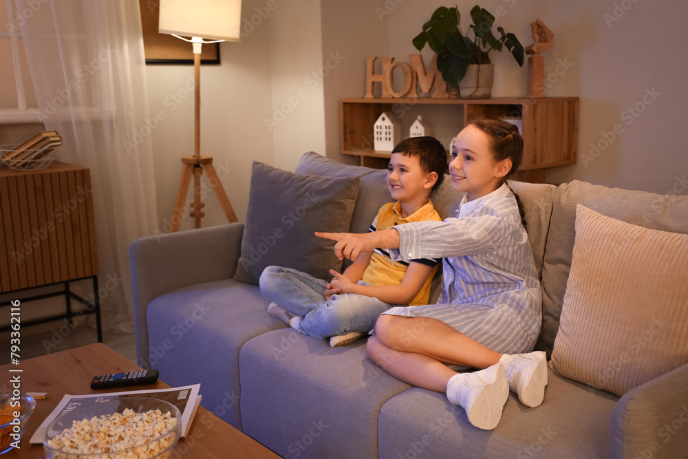 Little children watching TV on sofa at home in evening Little children watching TV on sofa at home in evening