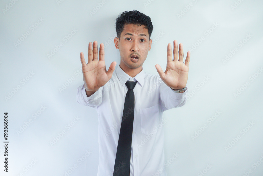 Adult Asian businessman looking camera and give stop hand sign with serious face expression Adult Asian businessman looking camera and give stop hand sign with serious face expression