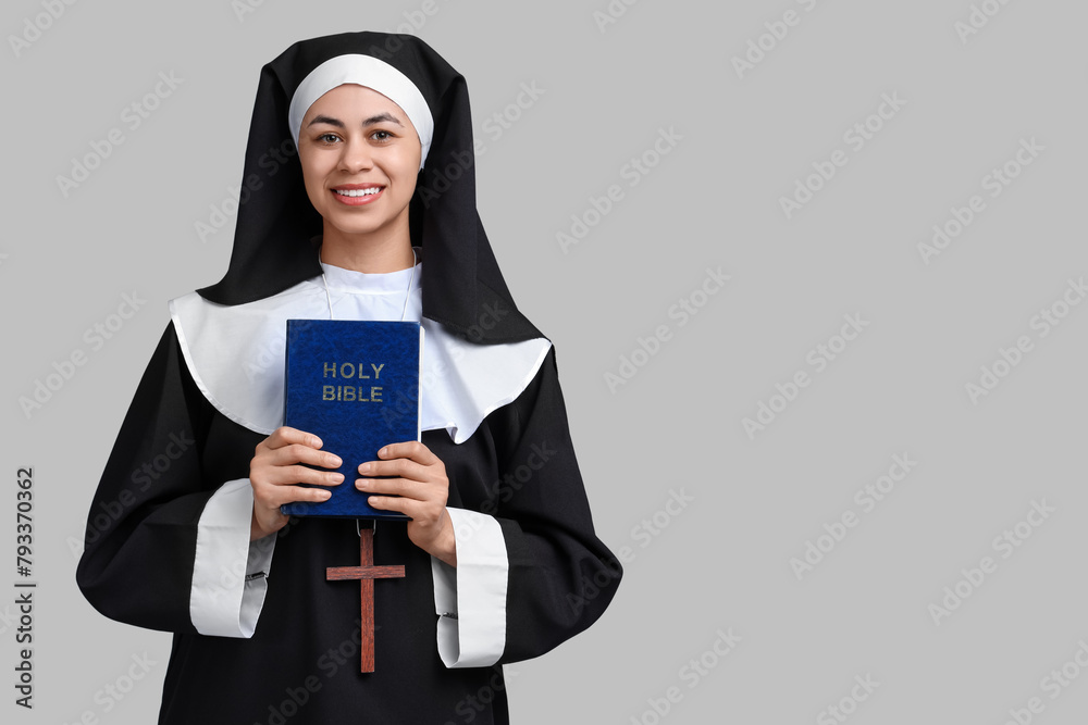 Portrait of young nun with Bible on grey background Portrait of young nun with Bible on grey background