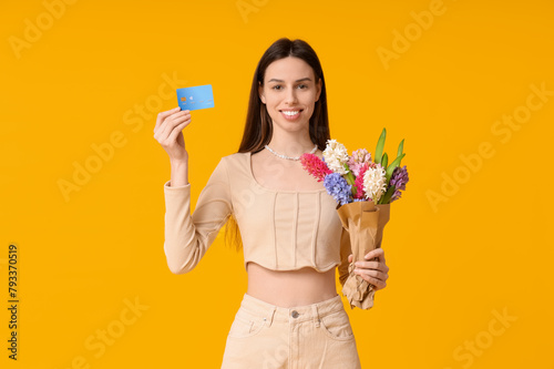Happy smiling young woman with bouquet of hyacinth flowers and credit card on...