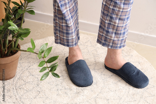 Legs of man wearing blue slippers at home. Closeup