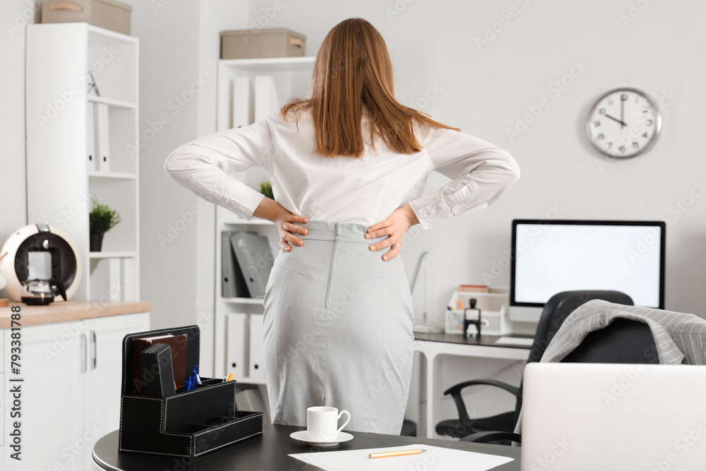 Fototapeta premium Young businesswoman suffering from back pain in office
