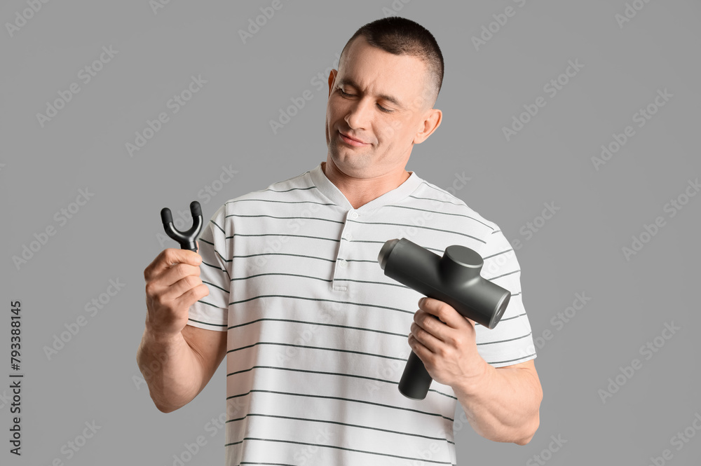 Young man with percussive massager and attachment on light background Young man with percussive massager and attachment on light background