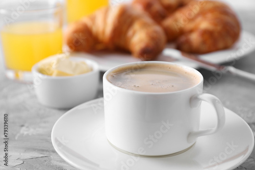 Tasty breakfast. Cup of coffee  butter and fresh croissants on grey table  closeup